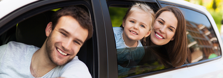 father, wife, and child in a car looking out the windows